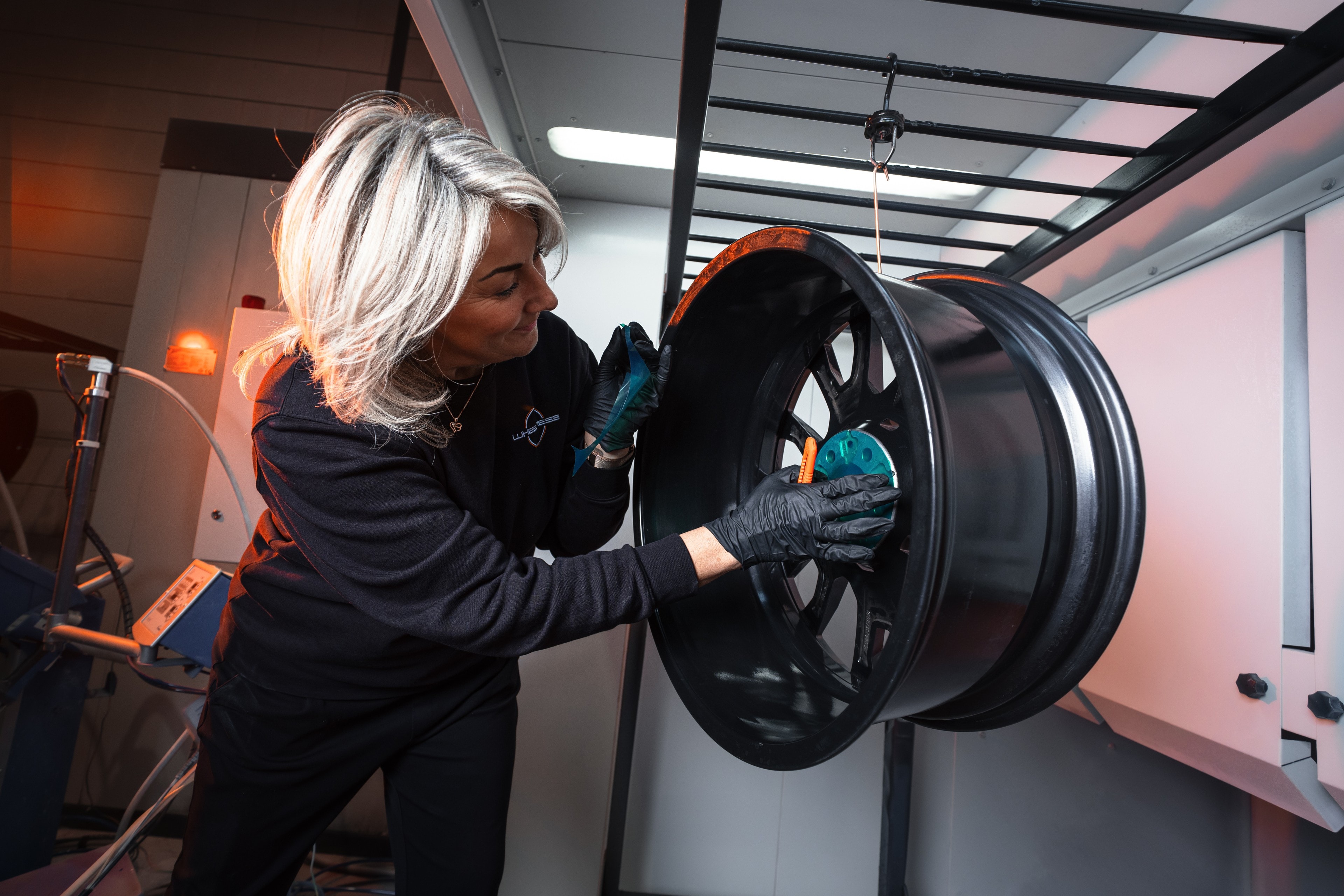 Kristel plakt een zwarte velg af in de spuitcabine